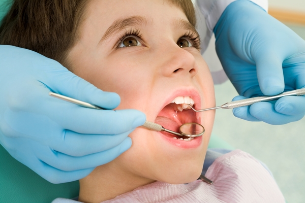 Kid in dental chair with mouth open