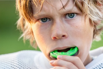 Image of boy with playing football wearing a mouth guard